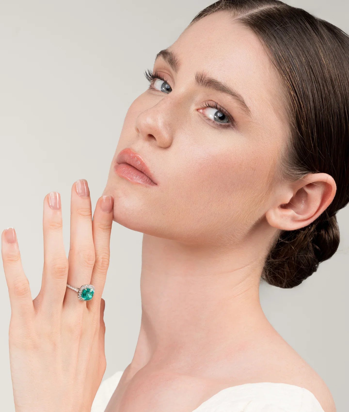 Woman wearing a "cushion paraiba halo" engagement ring, showcasing the ring's design.