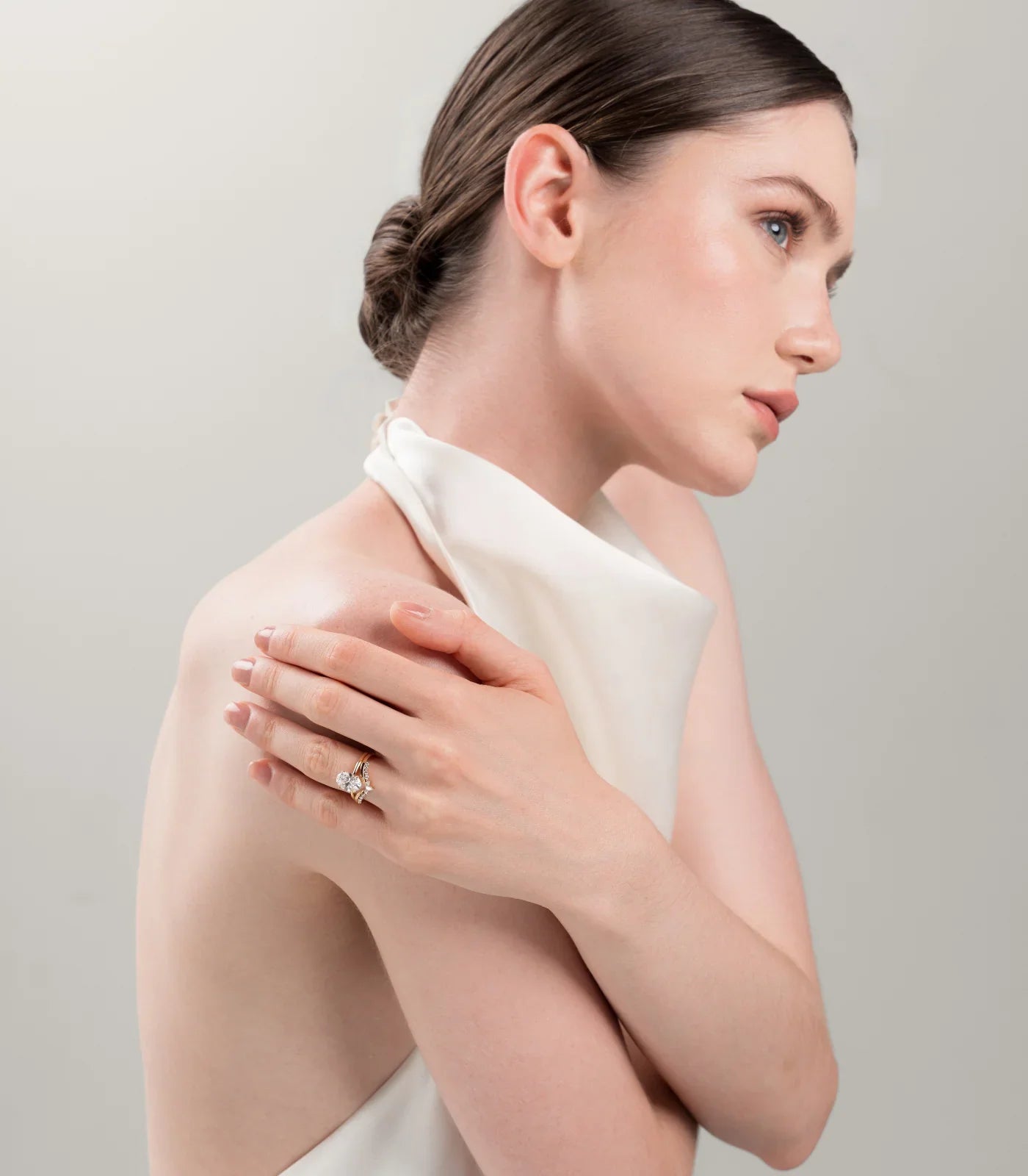 Woman wearing a "Keanis" bridal set with oval diamond and gold band.