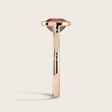 Side view of "Keanis" 18k rose gold solitaire ring. Lab-grown cushion ruby, bezel set.