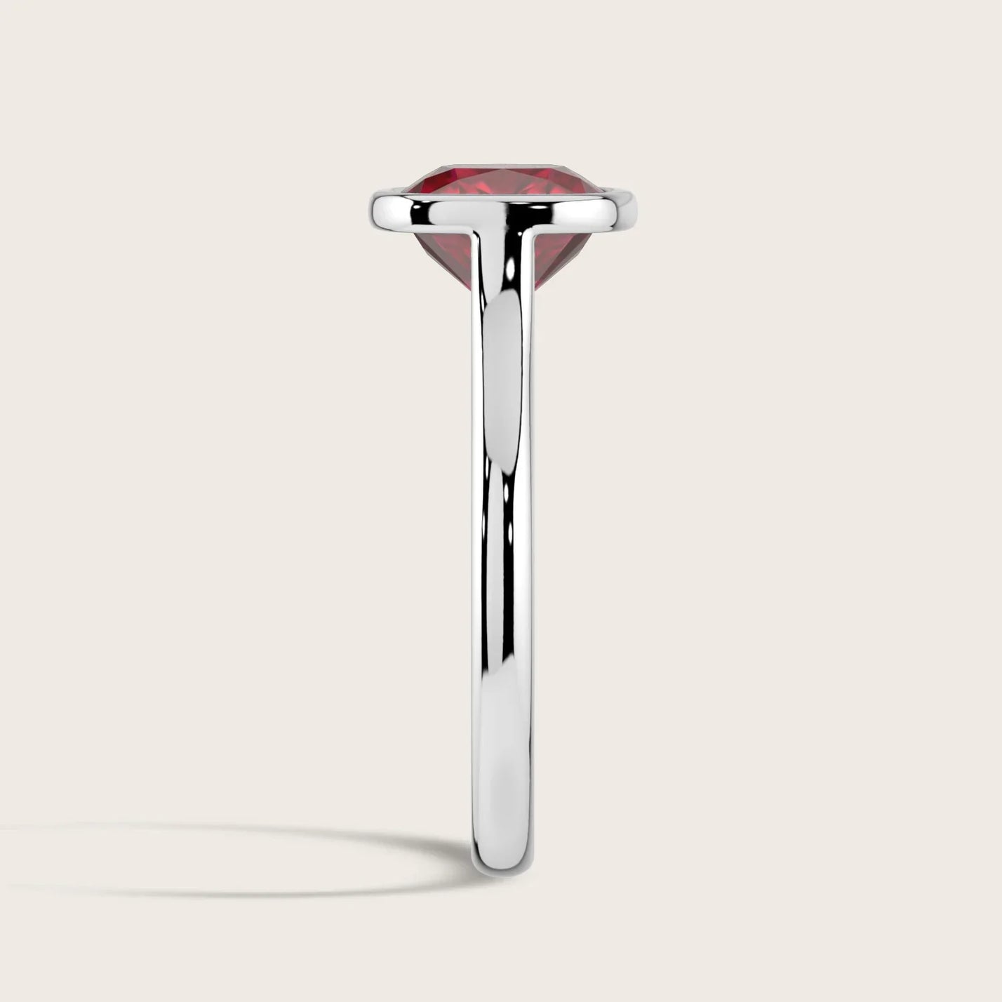 Side view of an 18k white gold solitaire ring with a bezel-set, cushion-cut, lab-grown ruby.