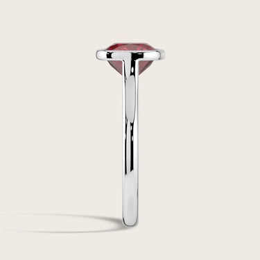 Side view of an 18k white gold solitaire ring with a bezel-set, cushion-cut, lab-grown ruby.