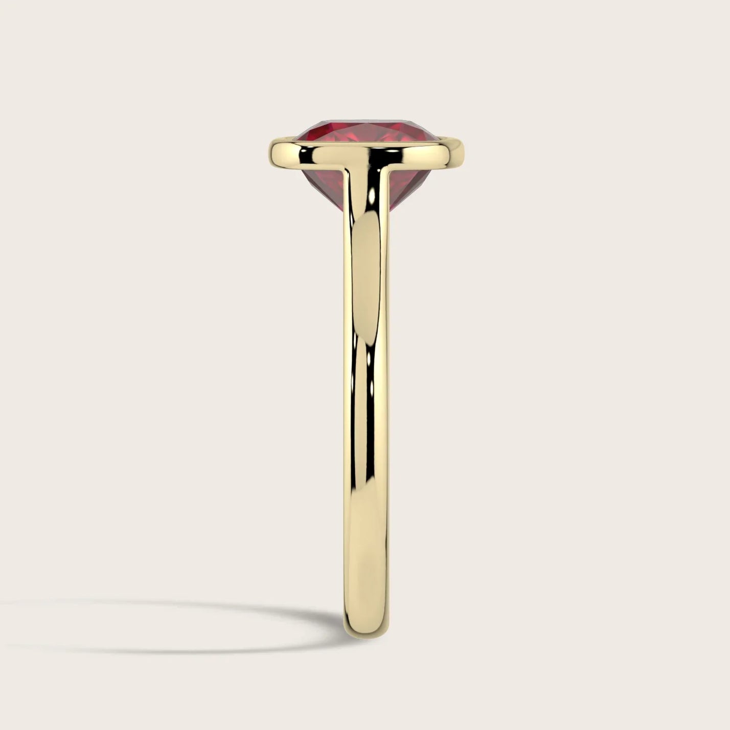 Side view of a lab-grown cushion ruby solitaire ring with a bezel setting in 18k yellow gold. "R25201CU.