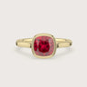 Cushion-cut lab-grown ruby solitaire engagement ring in 18k yellow gold, bezel set.