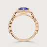 Side view of "lab-grown cushion sapphire" ring. Rose gold band, diamond halo, unique setting detail.