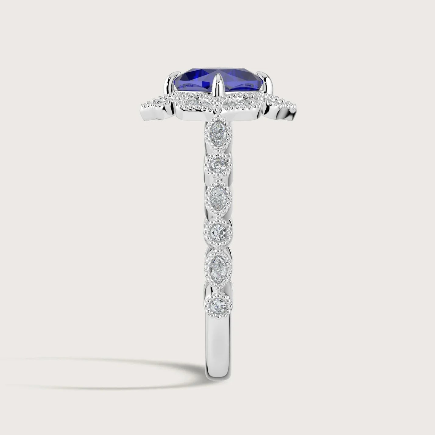 Lab-grown "cushion sapphire" ring. Halo setting with diamond band in 18k white gold. Side view.