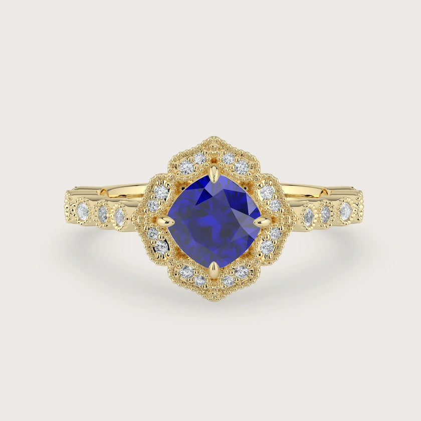 Lab-grown" cushion sapphire engagement ring. Diamond halo, 18k yellow gold band, vintage-inspired design.