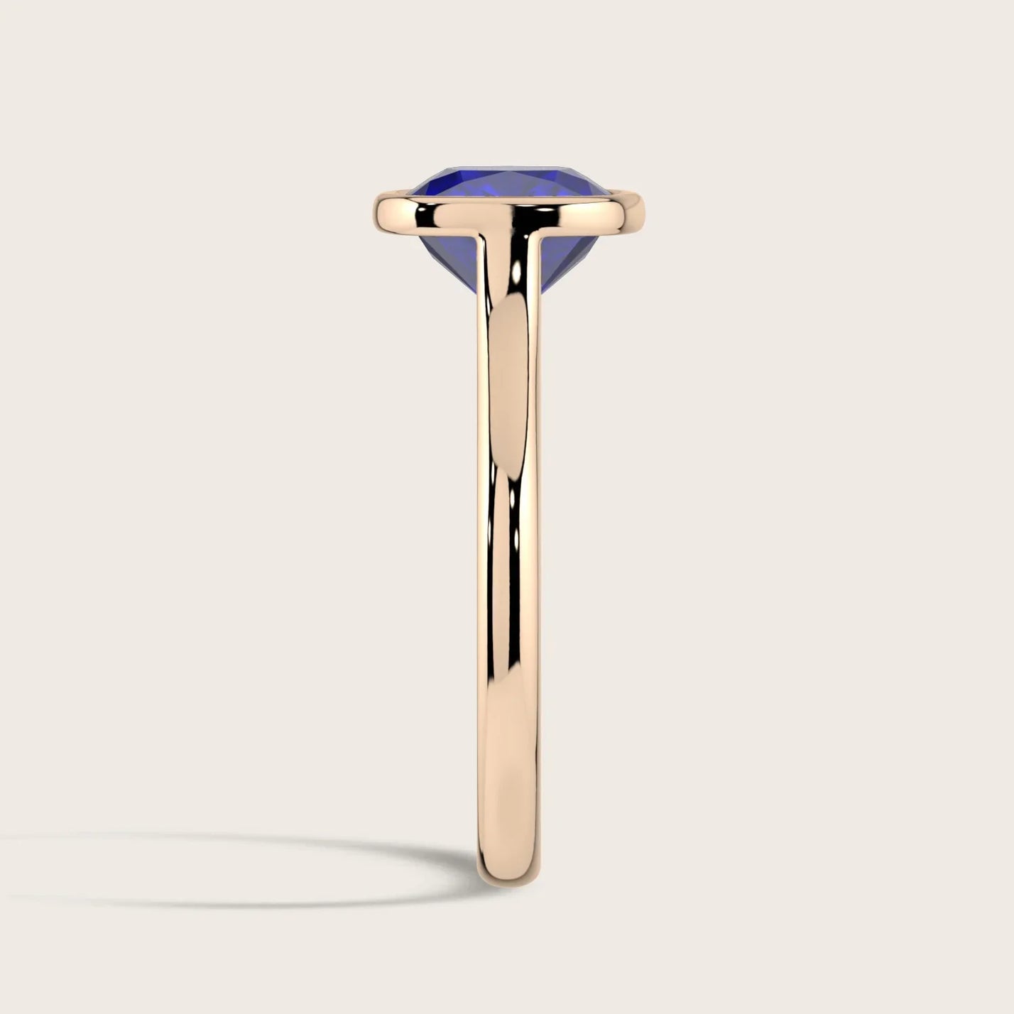 Side view of "lab-grown cushion sapphire" ring. Bezel set in 18k rose gold, solitaire style.