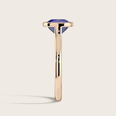 Side view of "lab-grown cushion sapphire" ring. Bezel set in 18k rose gold, solitaire style.