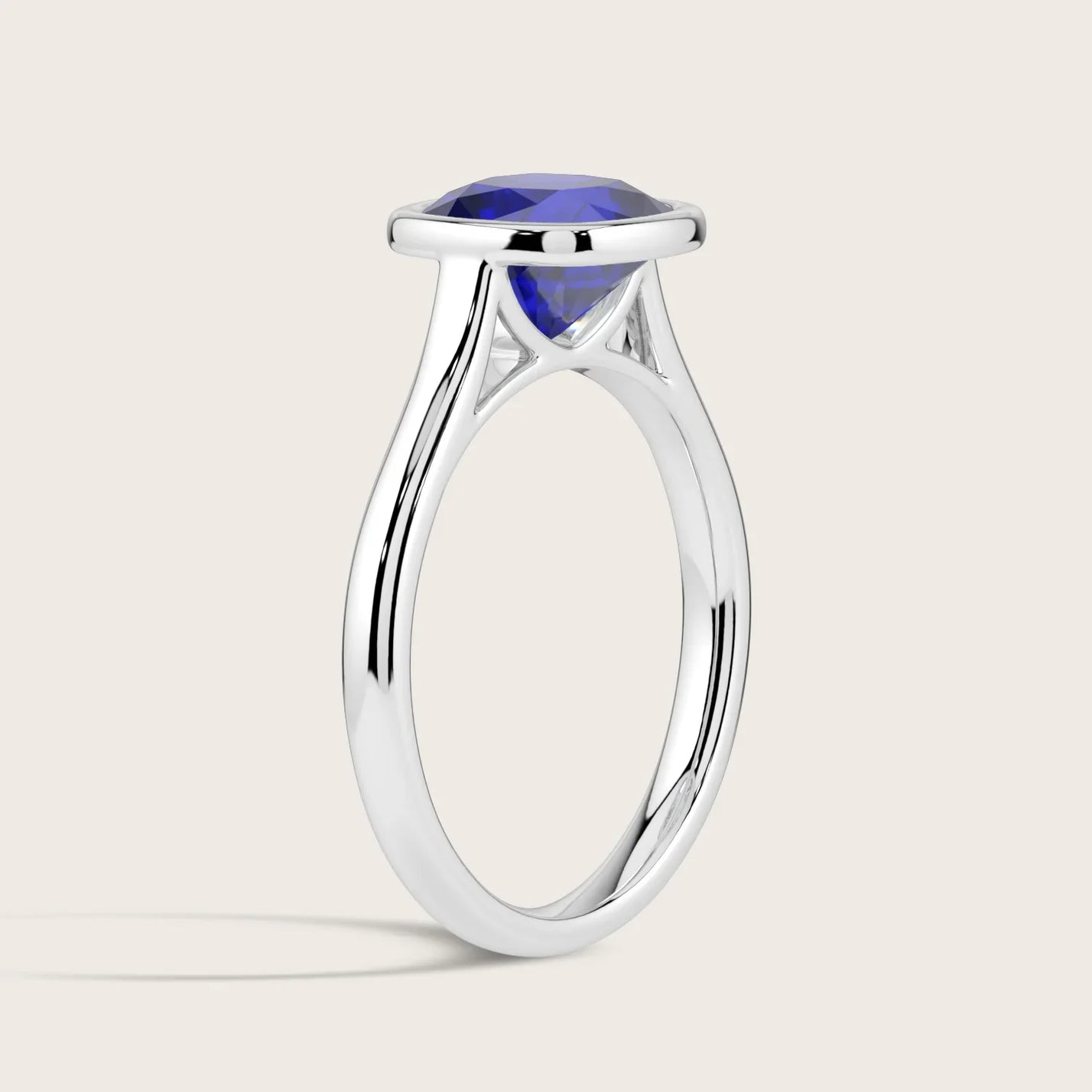 Lab-grown cushion sapphire solitaire ring. Bezel set in 18k white gold. Side view.