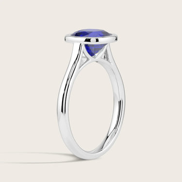 Lab-grown cushion sapphire solitaire ring. Bezel set in 18k white gold. Side view.