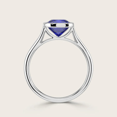 Lab-grown cushion sapphire solitaire ring. Bezel-set in 18k white gold, "R25201CU". Modern, elegant design.