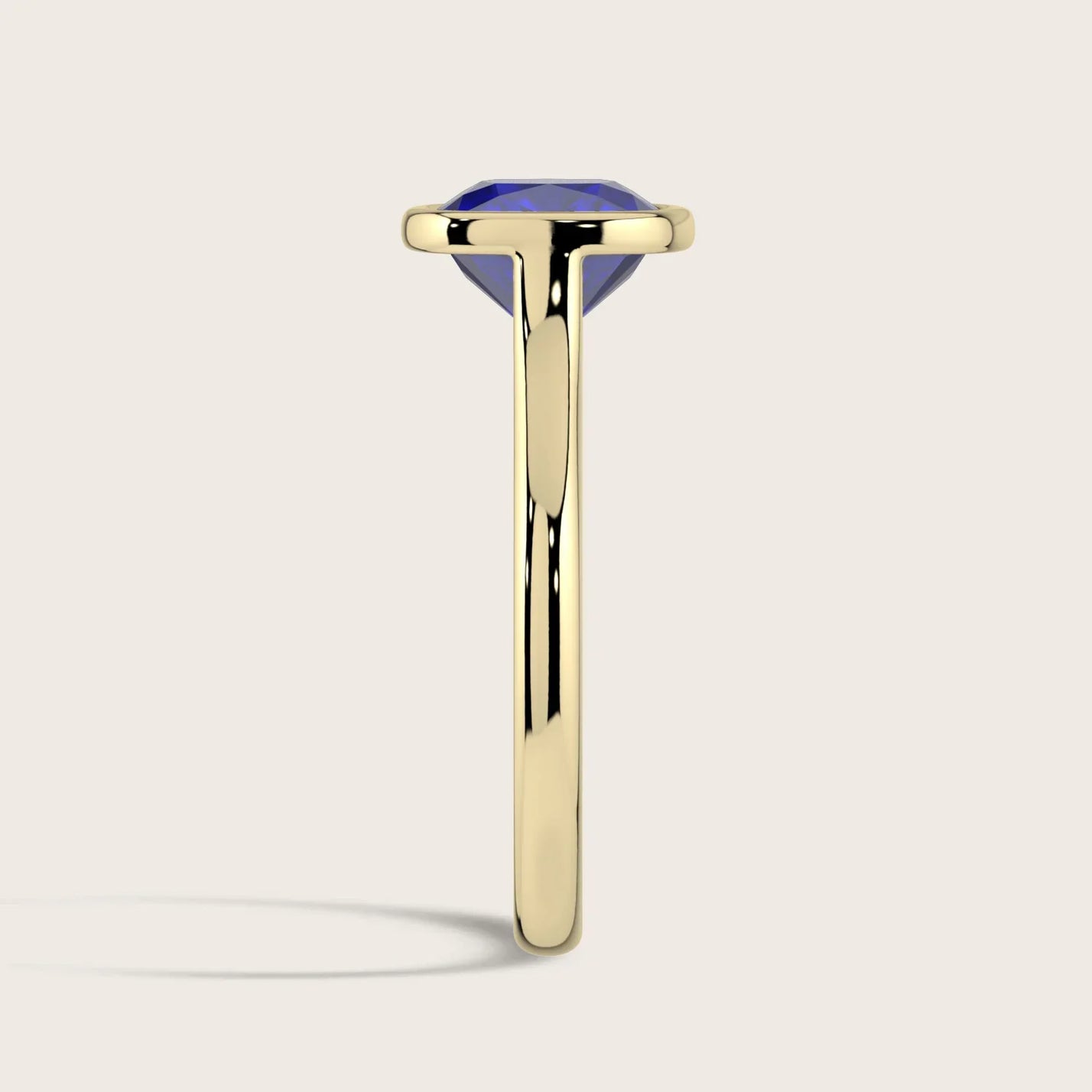 Side view: Lab-grown cushion sapphire solitaire ring, bezel set in 18k yellow gold.