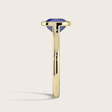 Side view: Lab-grown cushion sapphire solitaire ring, bezel set in 18k yellow gold.
