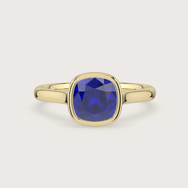 Lab-grown" cushion sapphire solitaire engagement ring in 18k yellow gold, bezel setting.