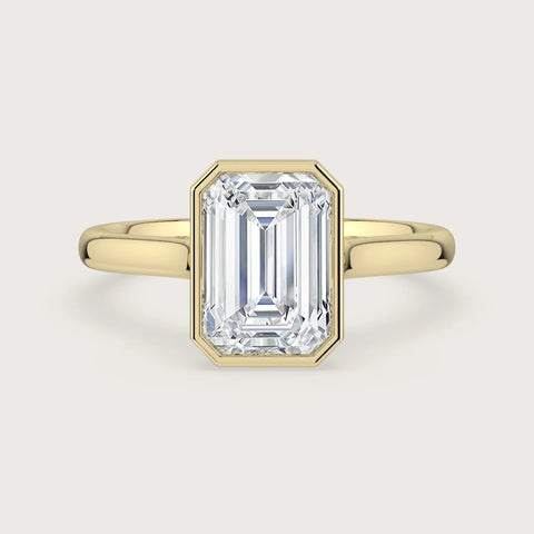 Lab-grown" emerald cut diamond solitaire engagement ring in 18k yellow gold bezel setting.