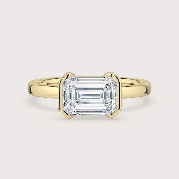 18k yellow gold engagement ring with lab-grown emerald cut diamond in "half bezel" setting. Solitaire ring.