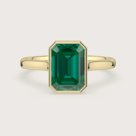 Lab-grown emerald "R25201EM" solitaire ring. 18k yellow gold bezel setting. Emerald cut gemstone.