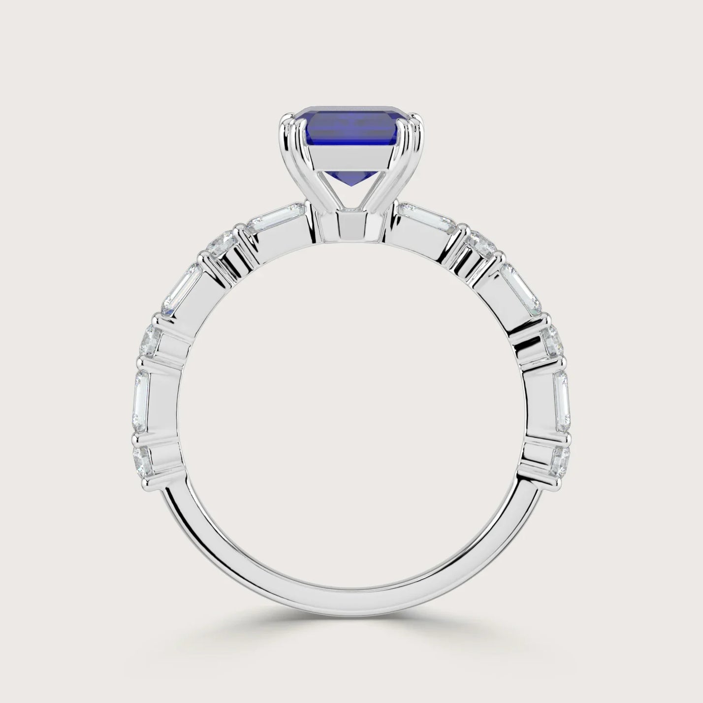 Lab-grown" sapphire ring in 18k white gold. Features emerald cut diamonds along the band. Side view.
