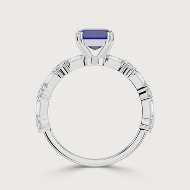 Lab-grown" sapphire ring in 18k white gold. Features emerald cut diamonds along the band. Side view.