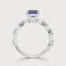 Lab-grown" sapphire ring in 18k white gold. Features emerald cut diamonds along the band. Side view.