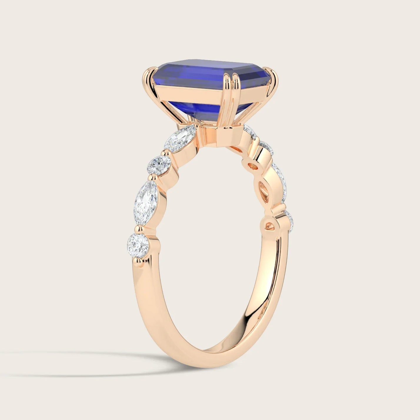 Rose gold ring with emerald-cut sapphire and marquise & round diamond band.