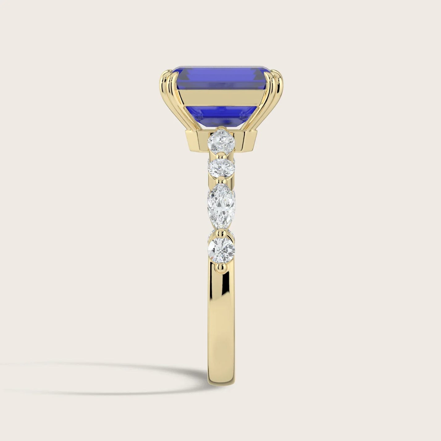 Side view of an 18k yellow gold ring with a lab-grown emerald-cut sapphire and round/marquise diamonds.