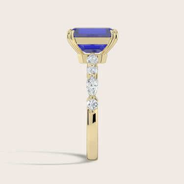 Side view of an 18k yellow gold ring with a lab-grown emerald-cut sapphire and round/marquise diamonds.