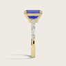 Side view of an 18k yellow gold ring with a lab-grown emerald-cut sapphire and round/marquise diamonds.