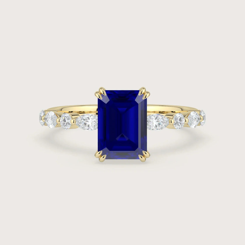 Yellow gold engagement ring with emerald-cut sapphire and lab-grown diamond band.