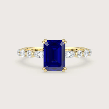 Yellow gold engagement ring with emerald-cut sapphire and lab-grown diamond band.