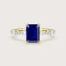 Yellow gold engagement ring with emerald-cut sapphire and lab-grown diamond band.