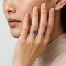 Woman wearing lab-grown "emerald-cut sapphire" solitaire ring in 18k rose gold half bezel setting.
