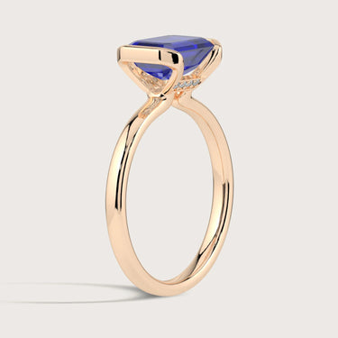 Rose gold "half bezel" ring with lab-grown sapphire solitaire and accent diamonds.