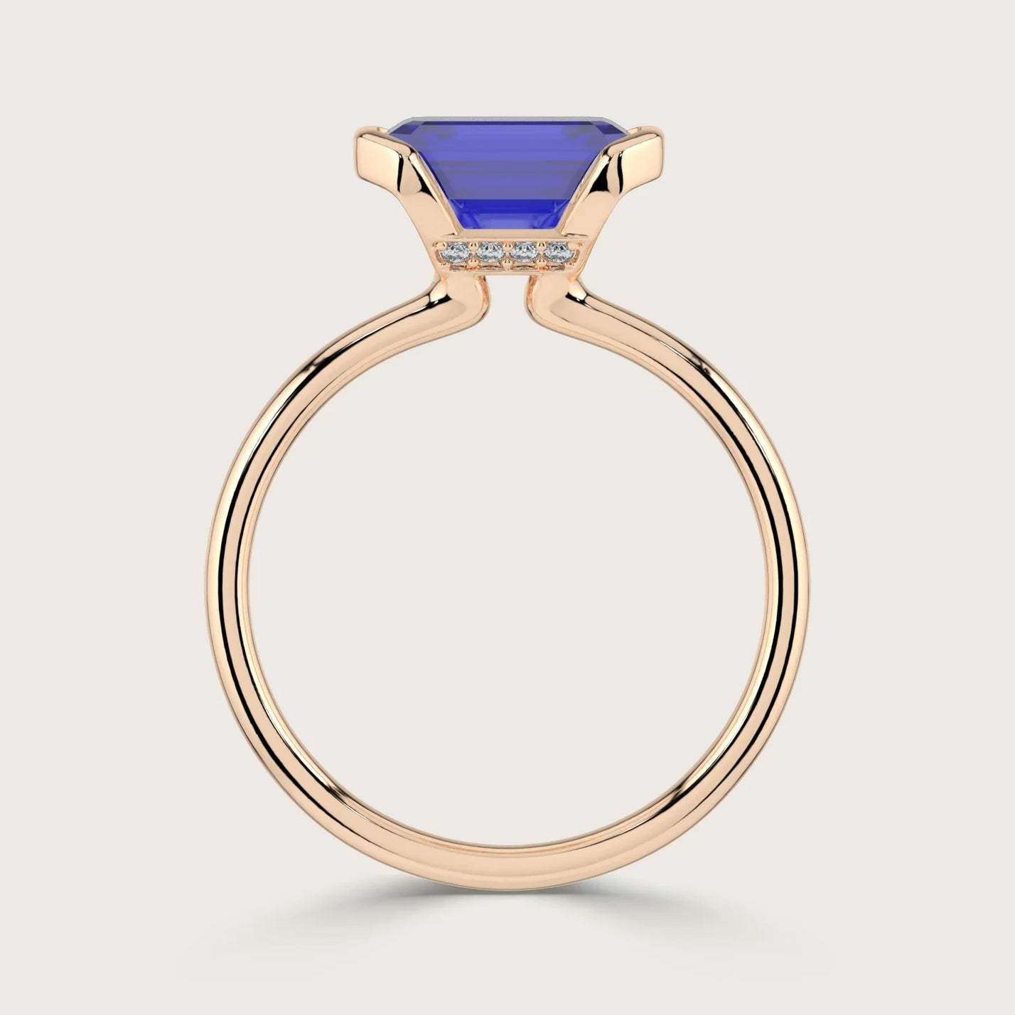 Lab-grown" sapphire ring. Emerald-cut blue stone in half-bezel setting with 18k rose gold band and small diamonds.