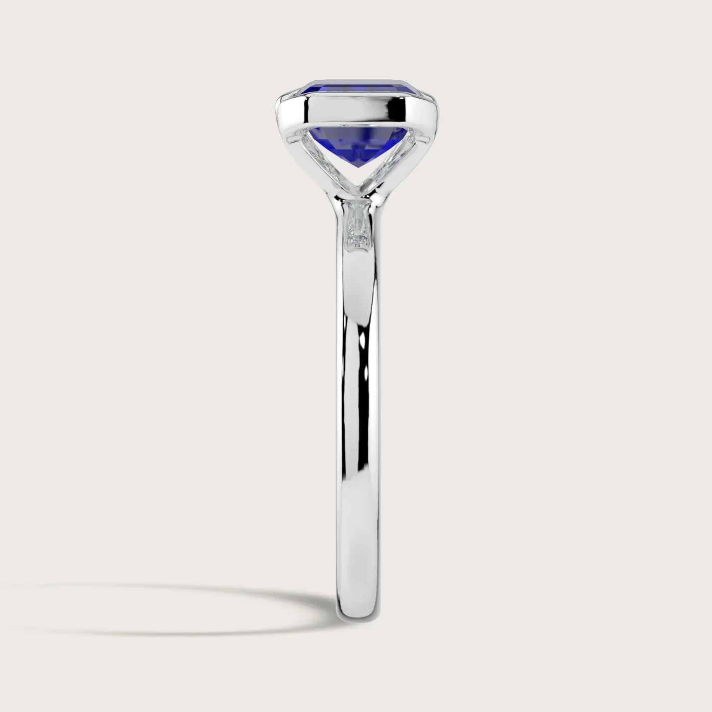 Side view of "R25201EM" lab-grown sapphire solitaire ring. Half bezel setting, 18k white gold band.