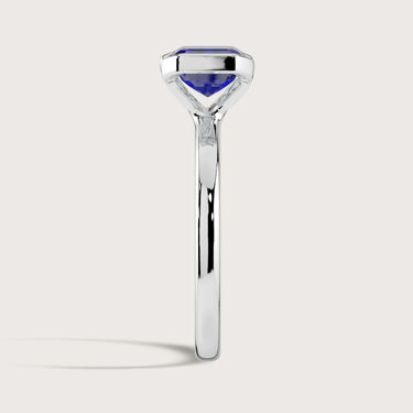 Side view of "R25201EM" lab-grown sapphire solitaire ring. Half bezel setting, 18k white gold band.