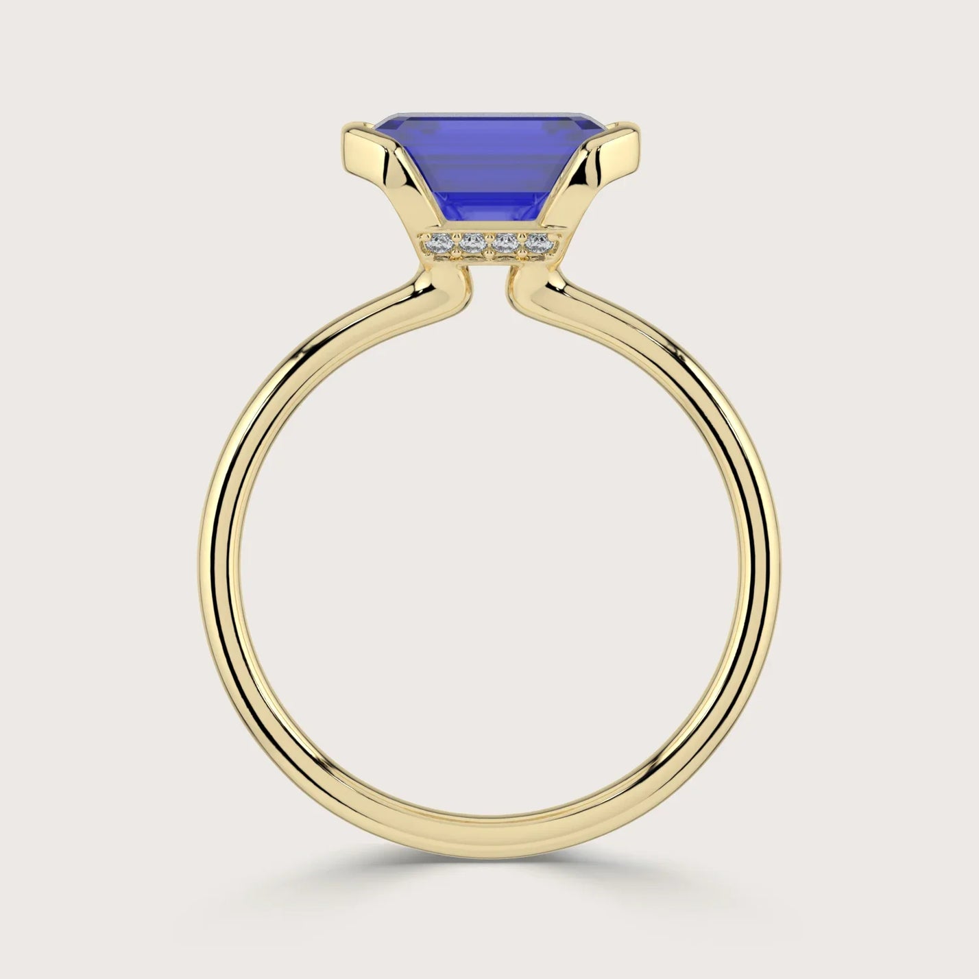 Lab-grown emerald-cut sapphire solitaire ring in 18k yellow gold with "half bezel" setting.