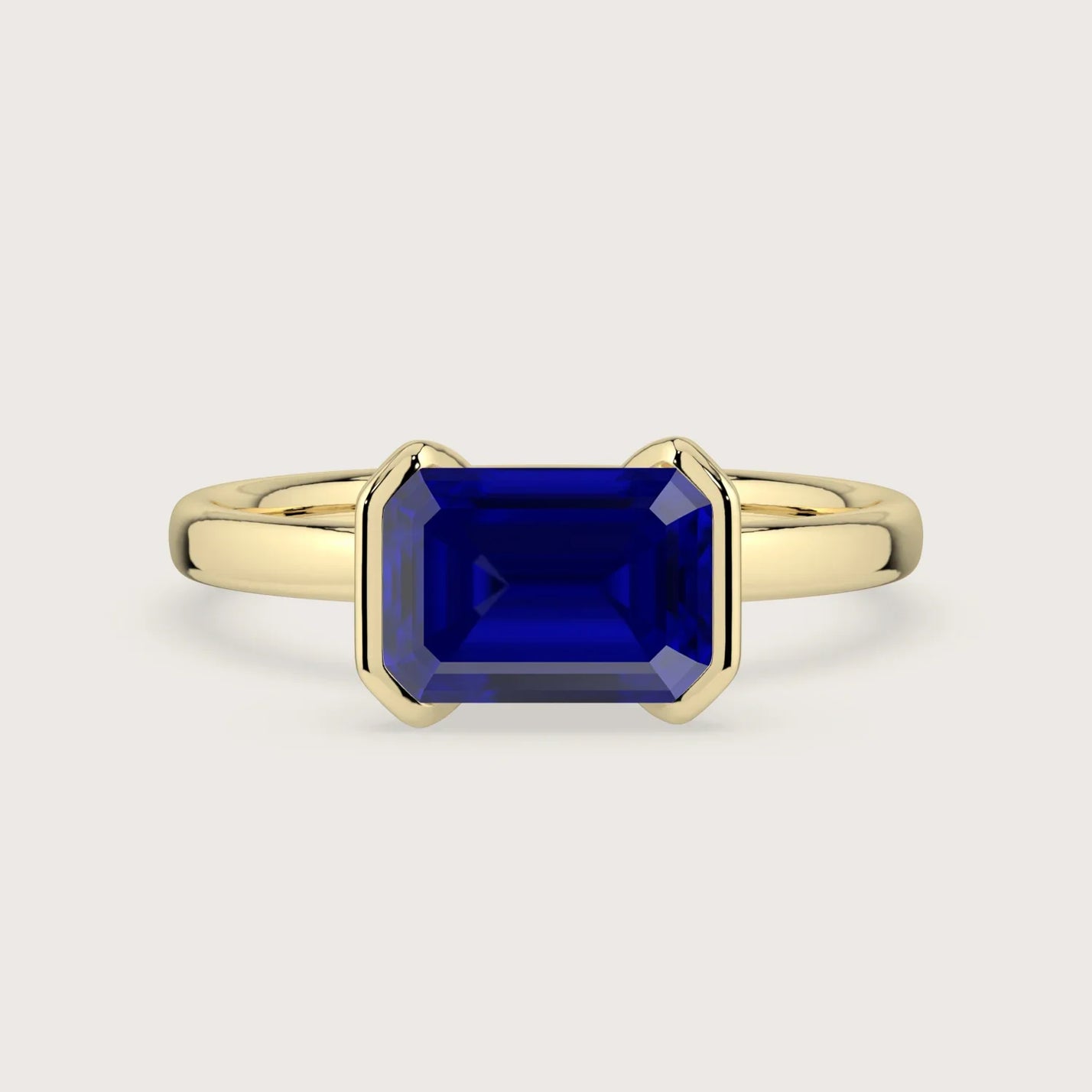 R25201EM" lab-grown sapphire ring. 18k yellow gold solitaire engagement ring with half bezel setting, emerald cut stone.
