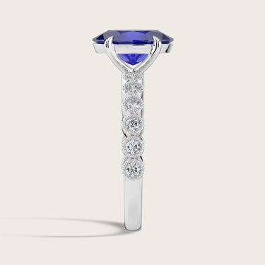 Lab-grown oval sapphire ring in 18k white gold with "milgrain" vintage diamond band, side view.