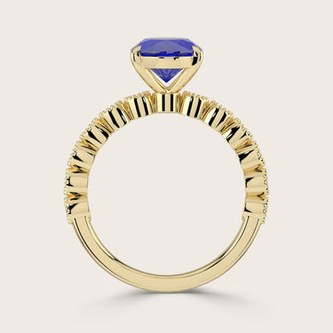 Close-up of an 18k yellow gold "milgrain" band ring with a lab-grown oval sapphire. Vintage style.