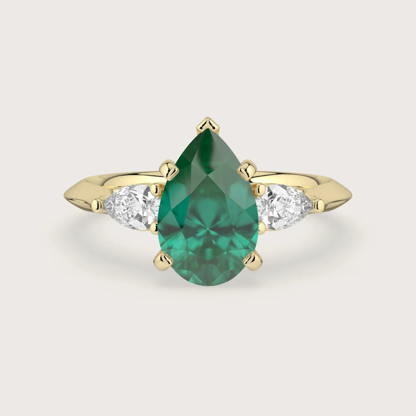 Pear-shaped emerald trilogy engagement ring in 18k yellow gold. Lab-grown gemstone ring.
