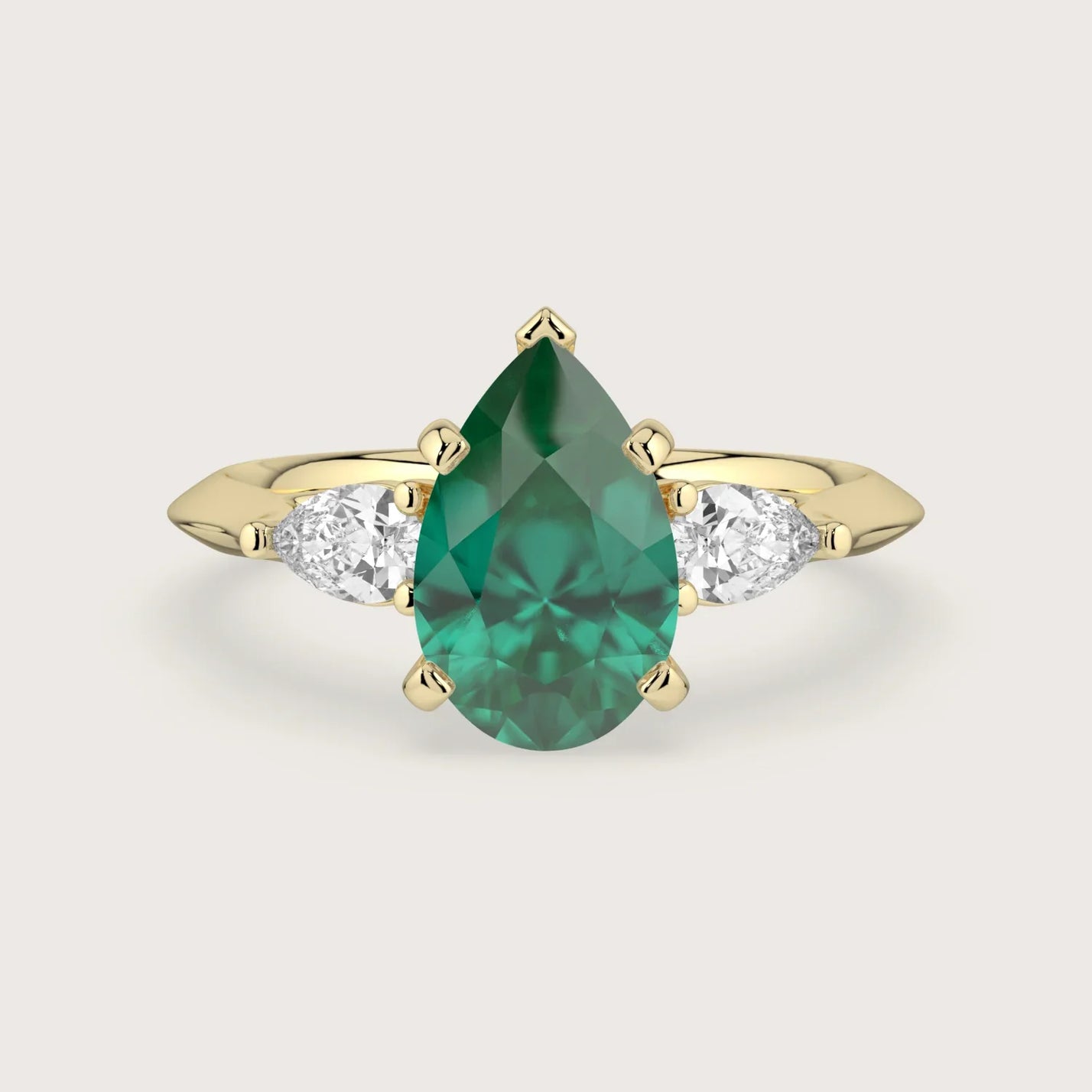 Pear-shaped emerald trilogy engagement ring in 18k yellow gold. Lab-grown gemstone ring.