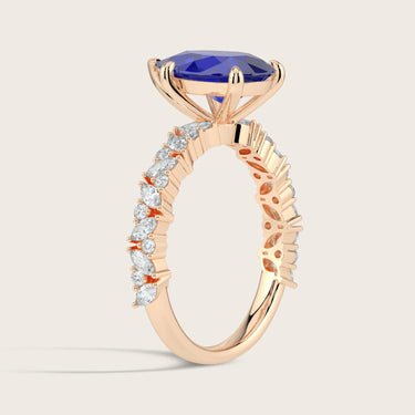 Rose gold ring with "lab-grown pear sapphire" and diamond band detail, side view.