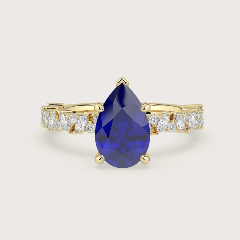 18k yellow gold engagement ring featuring a pear-shaped "lab-grown sapphire" and diamond band.