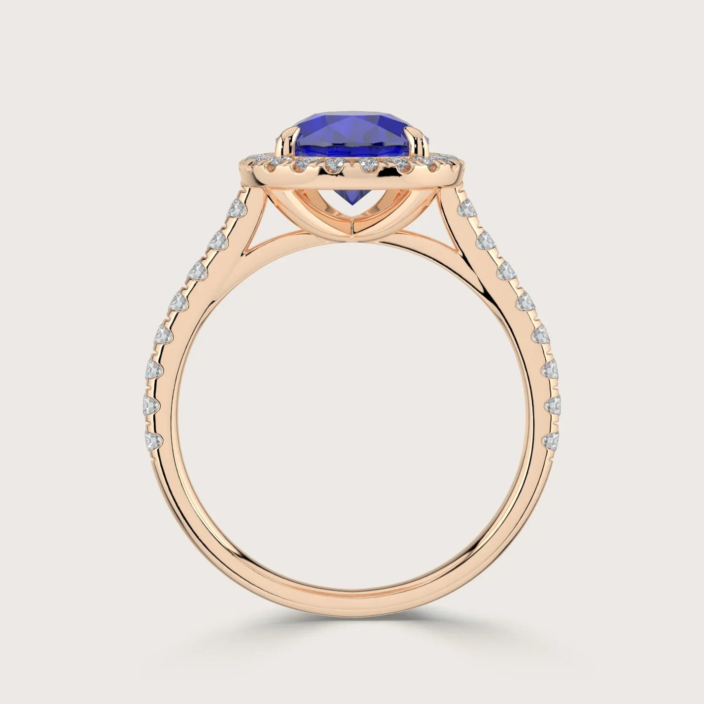 Rose gold ring with pear cut lab-grown sapphire, "halo" diamond setting, and diamond band.