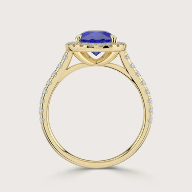 Close-up of a "lab-grown pear sapphire" ring with diamond halo and band in 18k yellow gold.