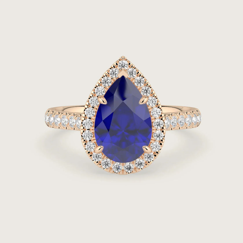 Pear-shaped lab-grown sapphire engagement ring with diamond halo and band in 18k rose gold.