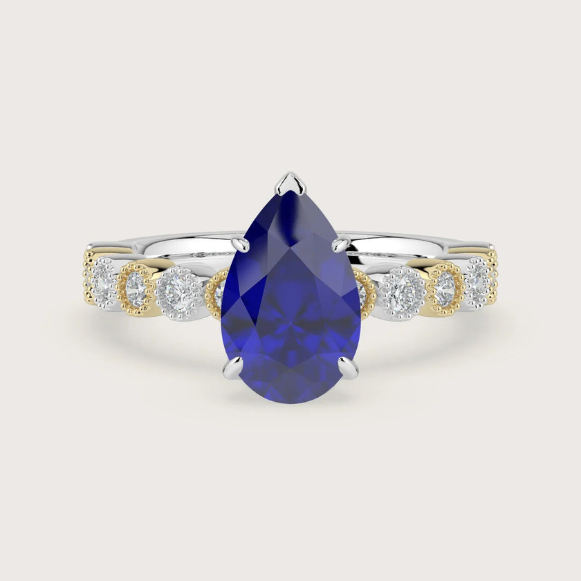 Lab-grown pear sapphire engagement ring. 18k two-tone band with milgrain detail and diamond accents.