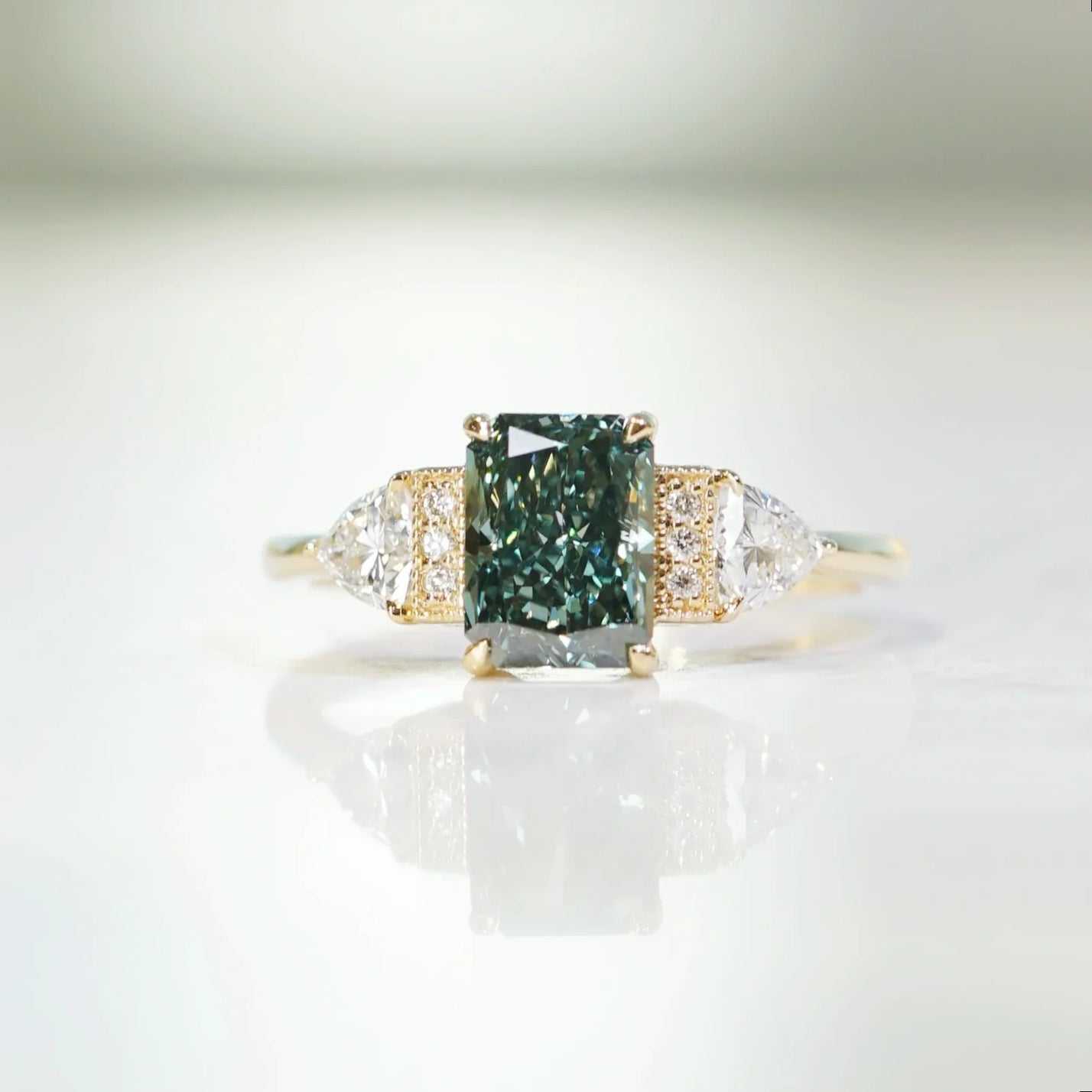 Lab-grown radiant green diamond ring. 18k yellow gold "The Chapters" design with side stones.
